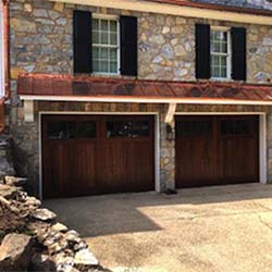 Wood garage doors on a two-story family home with stone veneer siding